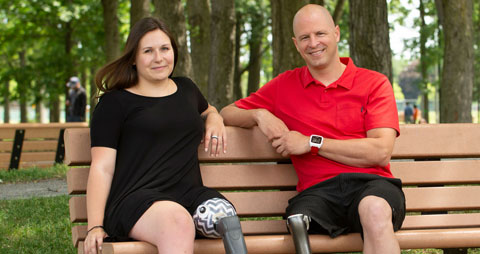 Une femme et un homme qui ont tous les deux une amputation à la jambe sont assis sur un banc de parc.
