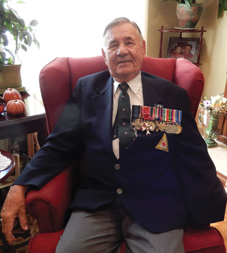 Bob Gondek, a Second World War amputee veteran is wearing medals from his war service while sitting on a chair.