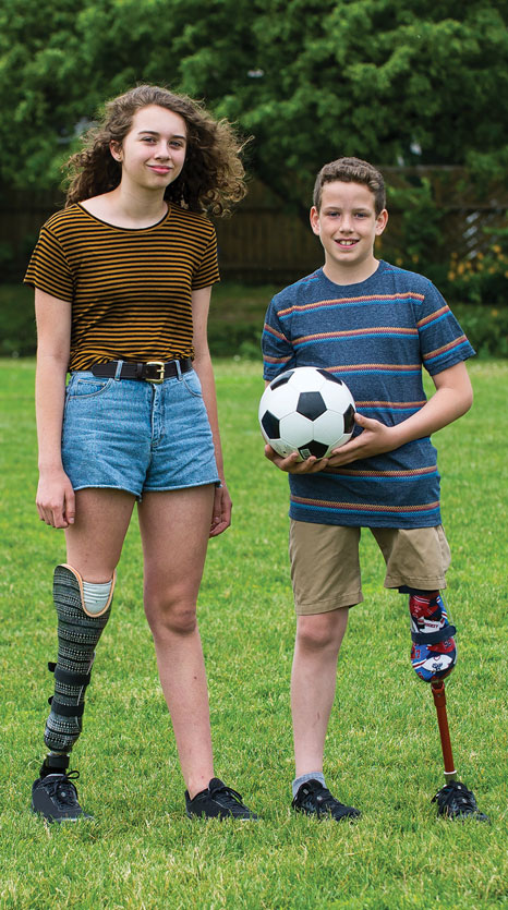 Une adolescente et un jeune garçon, tous les deux amputés d’une jambe, sur un terrain de football.