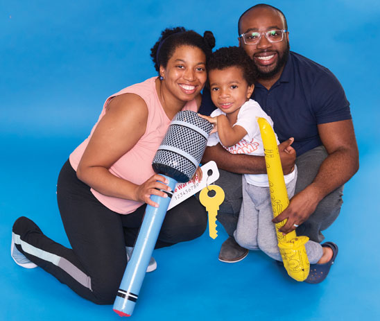 A young male double arm amputee is hugged on both sides by his mother and father.
