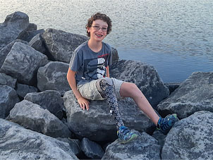Olivier assis sur un rocher au bord d'un lac.