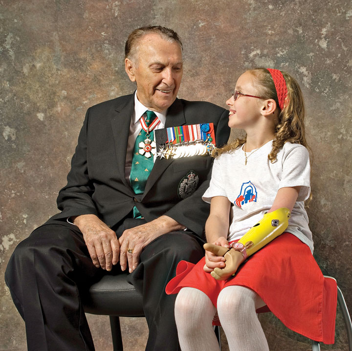 Cliff Chadderton, wearing his military medals, sits beside a young female arm amputee.