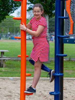 Éléonore, qui est amputée de la jambe, est debout sur une structure de terrain de jeu.