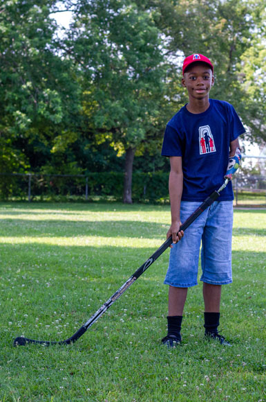 Sébastien, un jeune garçon amputé d’un bras, est dehors et tient un bâton de hockey.